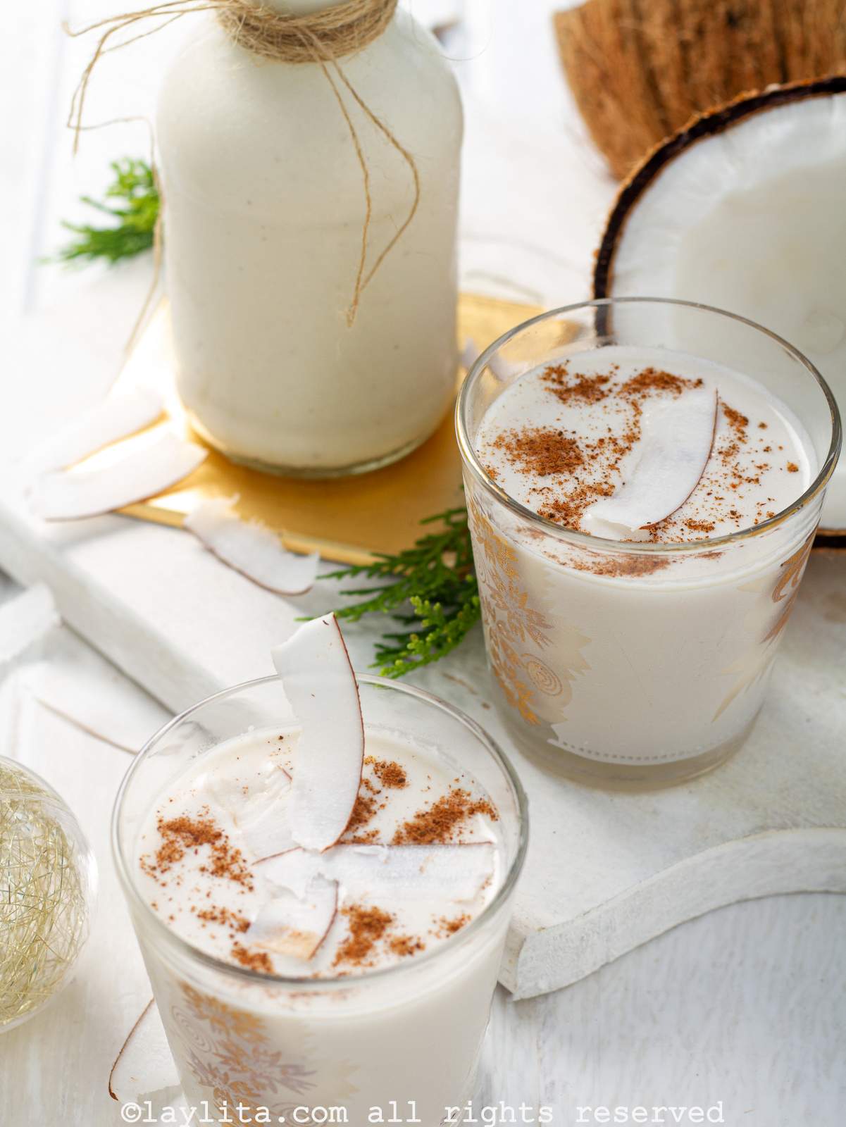 Overhead shot of a glass of coquito with another glass next to it.