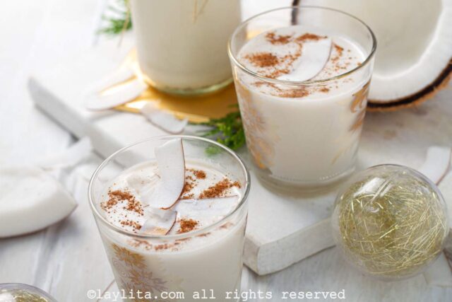 Coquito served in glasses with coconut ribbons and ground cinnamon sprinkled on top.