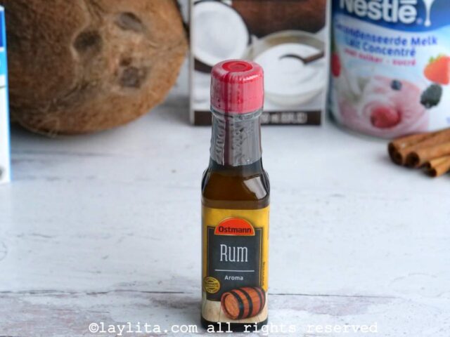 Small bottle of Rum essence or aroma with a coconut in the background