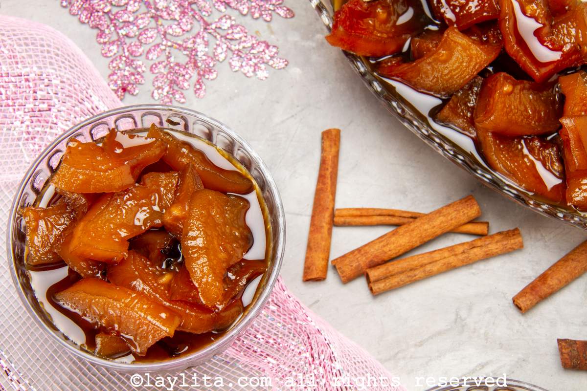 Overhead shot of candied papaya served in a glass with a bowl of it next to it.