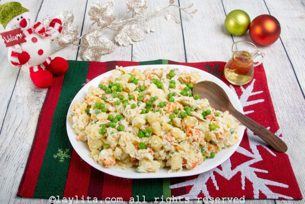 Ensalada de gallina served on a white serving platter on a Christmas place mat with Christmas decorations around it.