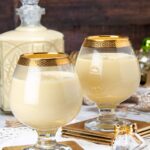 Two glasses with gold rims filled with ponche crema.