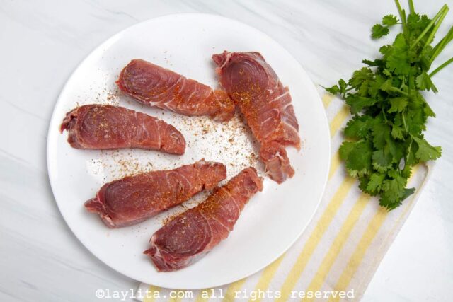 Albacore tuna seasoned with salt and pepper on a white plate