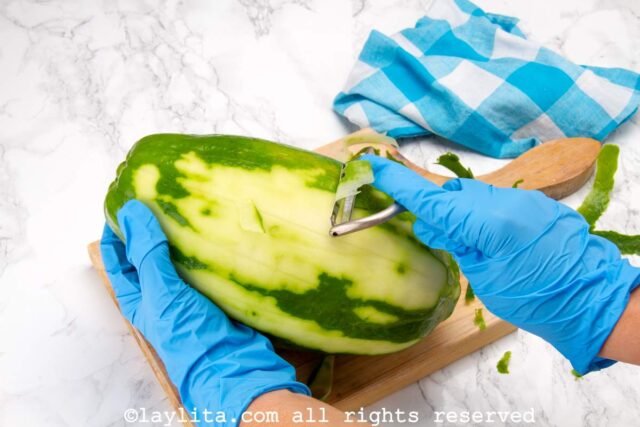 Peeling the papaya with a potato peeler.