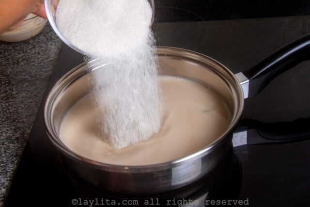 Sugar being added to the saucepan of coconut milk.