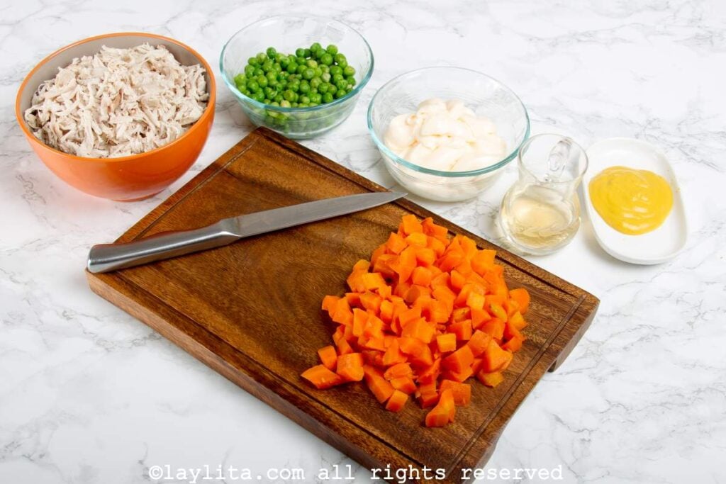 Diced carrots on a wooden cutting board.