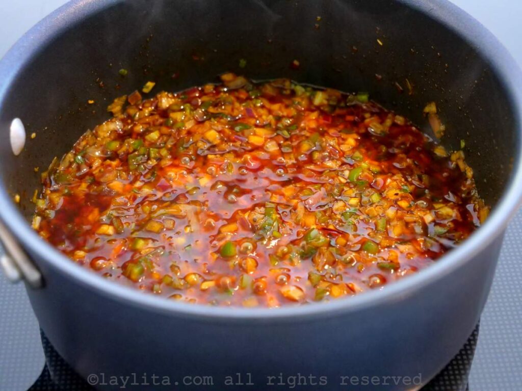 Cooking the refrito in a saucepan on the stove.
