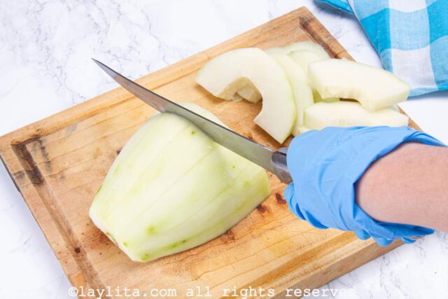 Slicing the green papaya on a wooden cutting board.