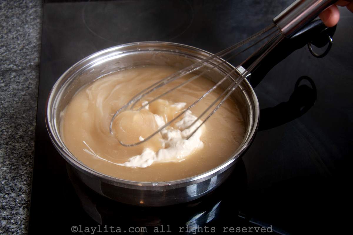 Coconut cream added to the pudding mixture in a saucepan.