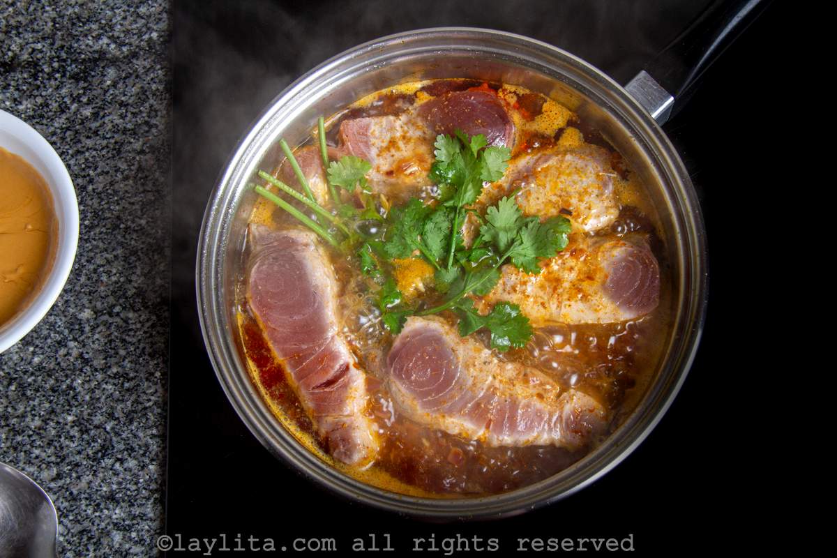 Fish simmering in a saucepan with the refrito and fresh cilantro.