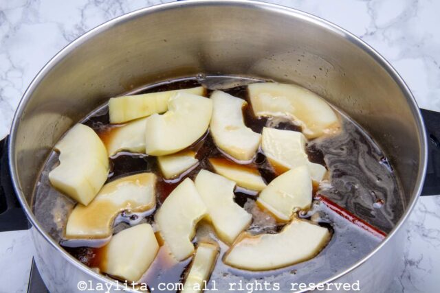 Green papaya slices being simmered in the syrup in a pot.