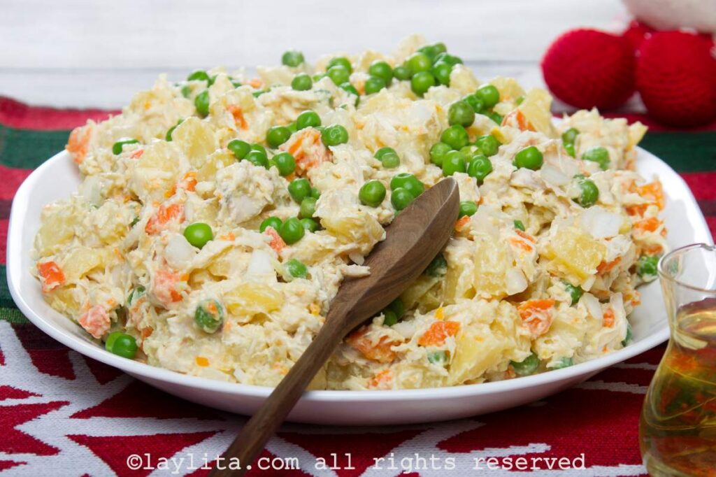 Ensalada de gallina served on a white serving platter on a Christmas place mat with Christmas decorations around it.