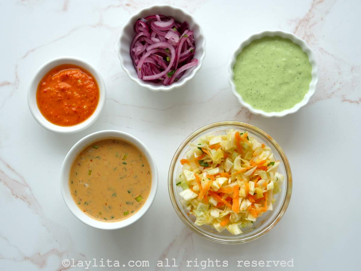 Sauces and toppings for Ecuadorian plantain corviche: Pickled red onions, cilantro mayo sauce, cabbage anc carrot salad, peanut sauce, spicy aji sauce