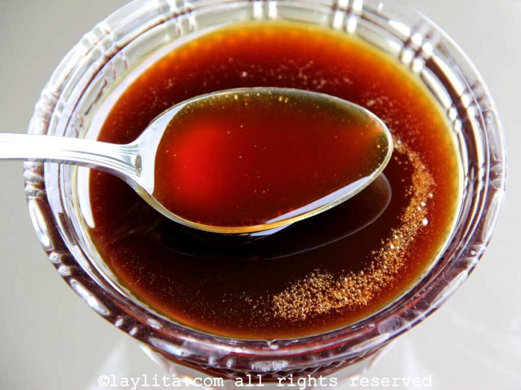 Almíbar de papelón in a clear glass bowl with a spoon