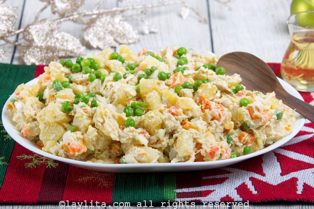 Ensalada de gallina or chicken salad served on a white serving platter with a wooden spoon.