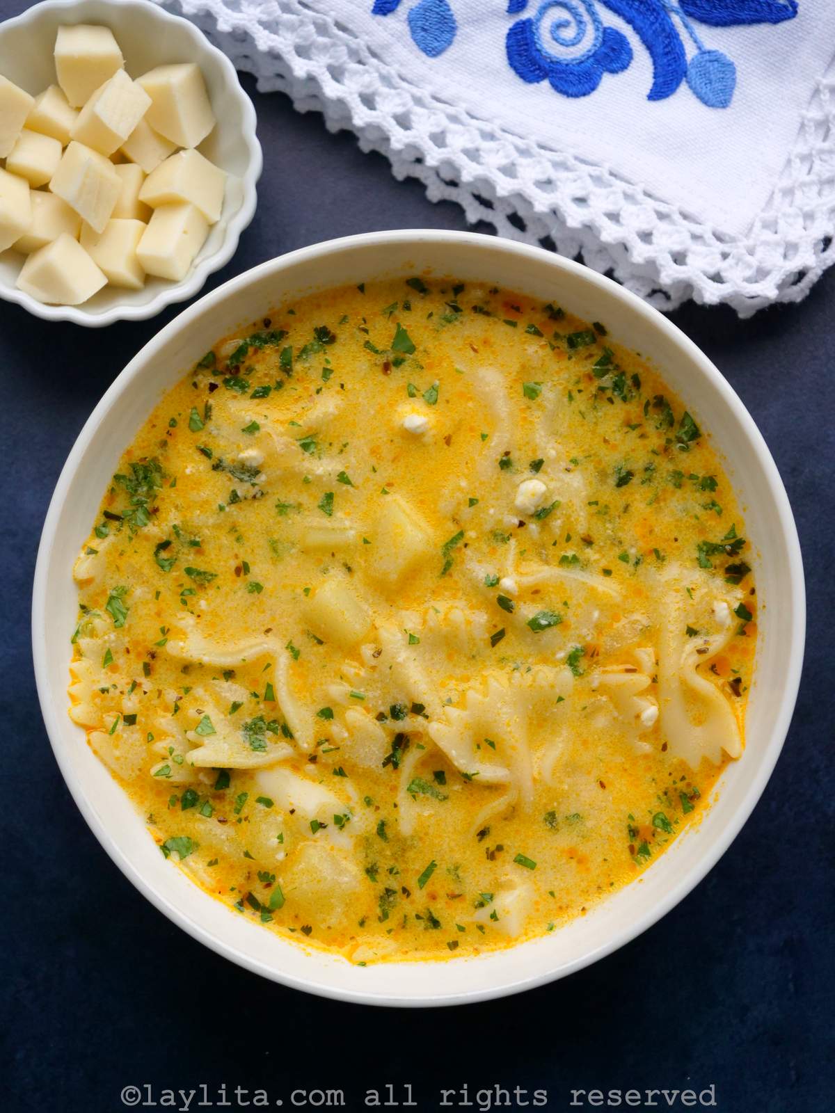 Sopa de fideo served in a white bowl next to a side of extra cheese and a napkin.