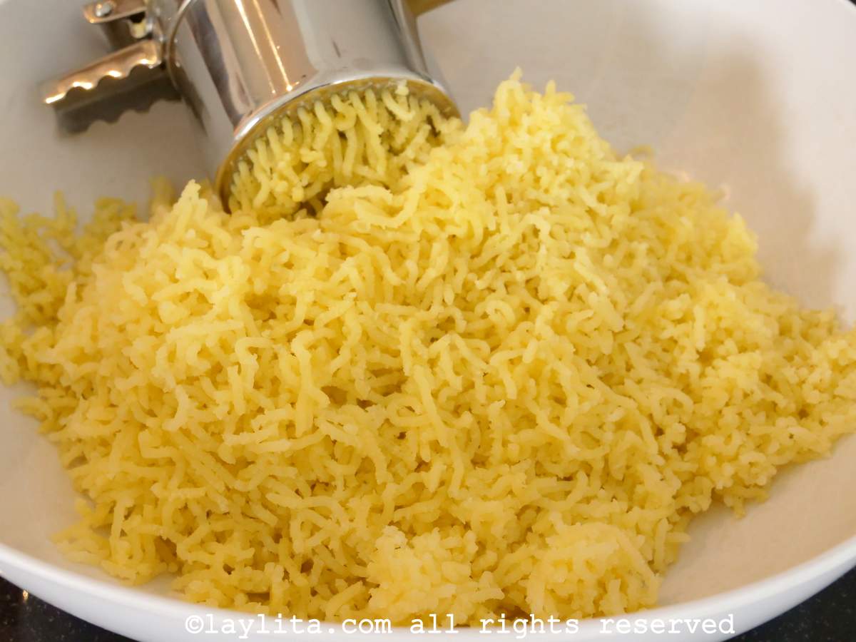 Using a potato ricer to mash the cooked potatoes.