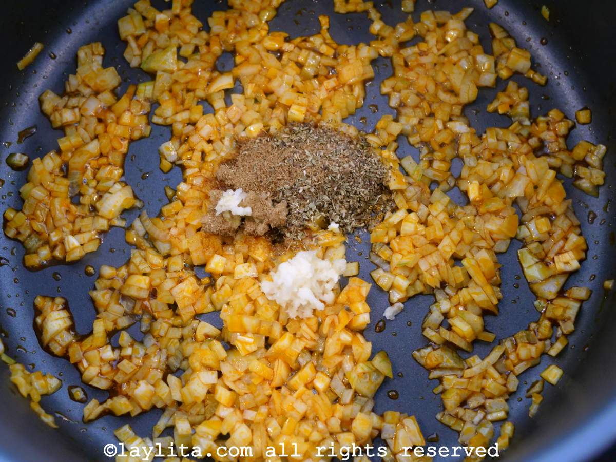 Crushed garlic and spices added to the onions in a pot.