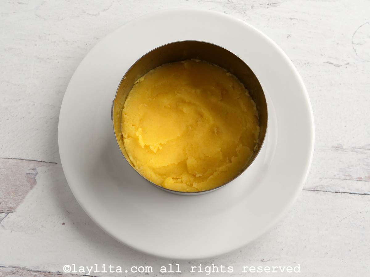 Ring mold on a plate with a layer of mashed potatoes at the bottom.