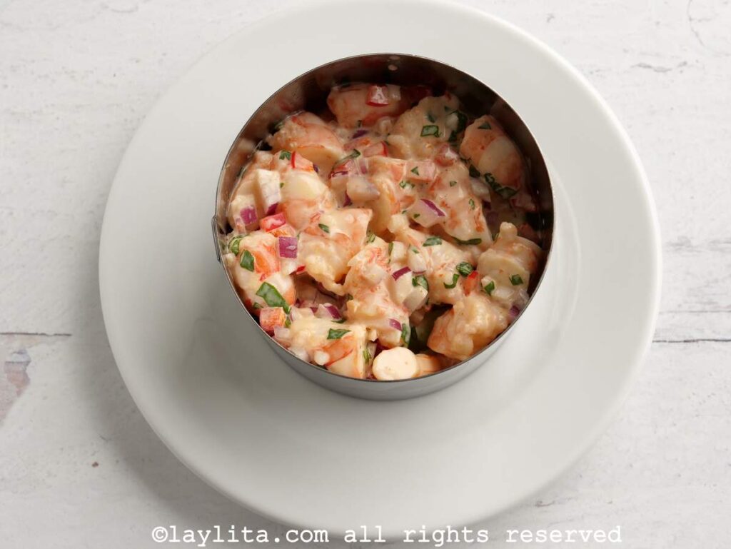 Layer of shrimp salad added to a circular mold on a plate