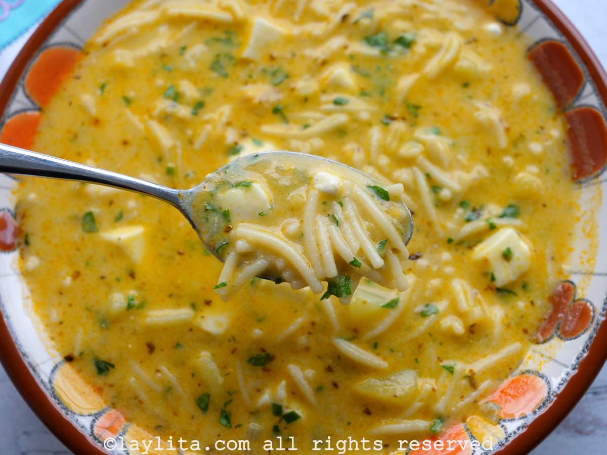Spoon scooping up a bite of fideo soup from a bowl.