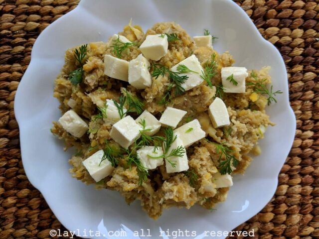 Overhead shot of Ecuadorian green plantain tigrillo served on a white plate with cubes of cheese and cilantro.