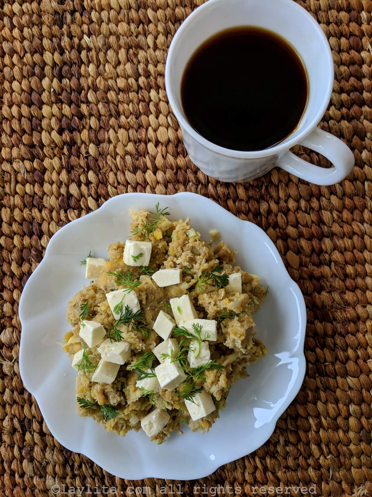 Ecuadorian green plantain tigrillo con queso served on a plate with a cup of coffee on the side. 