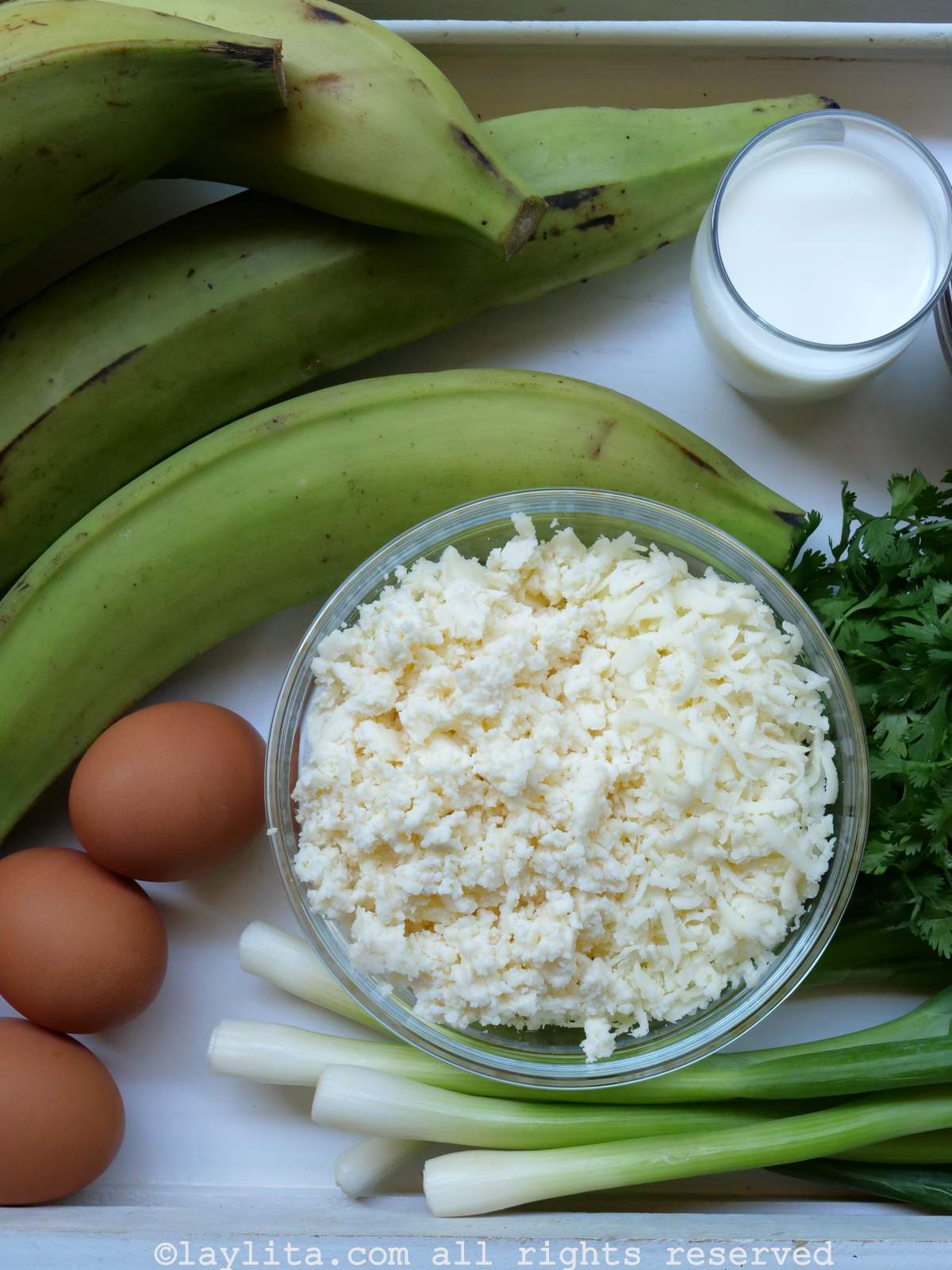 Ingredients for tigrillo o green plantain mash on a white table