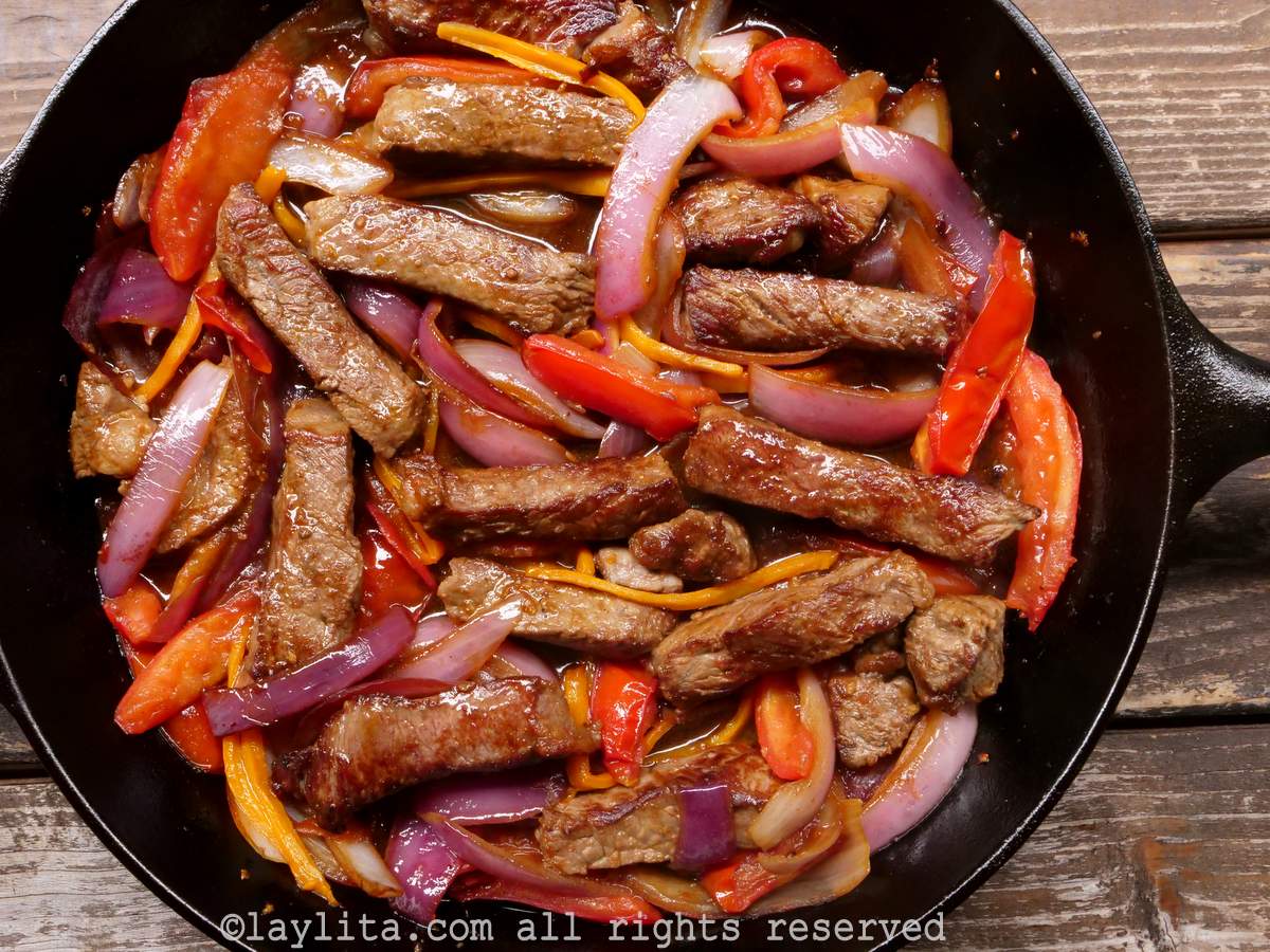 Overhead shot of lomo saltado in a cast iron dish after being mixed together.