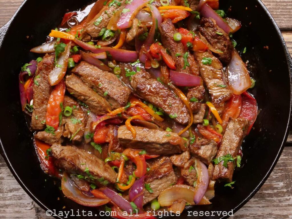 Overhead shot of lomo saltado in a cast iron dish after being mixed together.