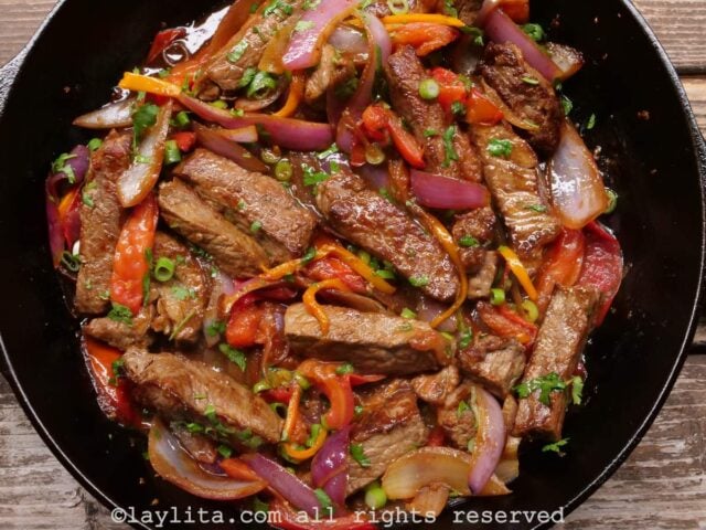 Overhead shot of lomo saltado in a cast iron dish after being mixed together.