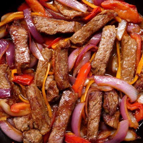 Overhead shot of lomo saltado in a cast iron dish after being mixed together.