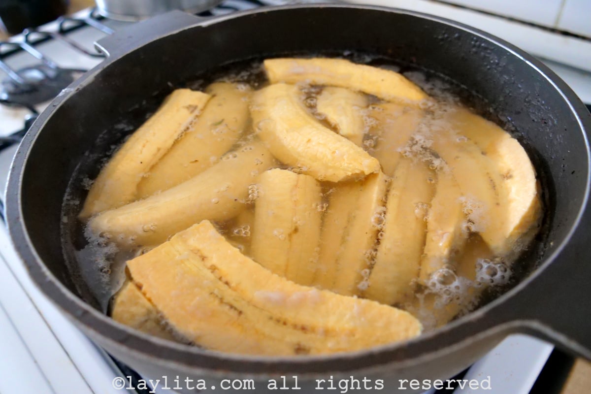 Slices of plantain boiling in a large pot of water. 