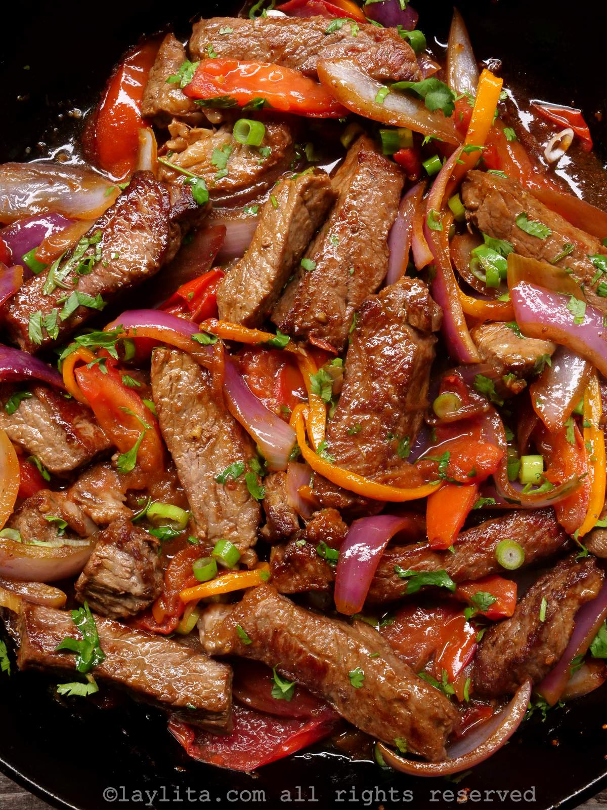 Overhead shot of lomo saltado in a cast iron dish after being mixed together.