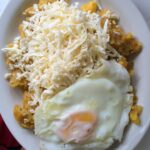 Ecuadorian tigrillo served with grated cheese and a fried egg on top