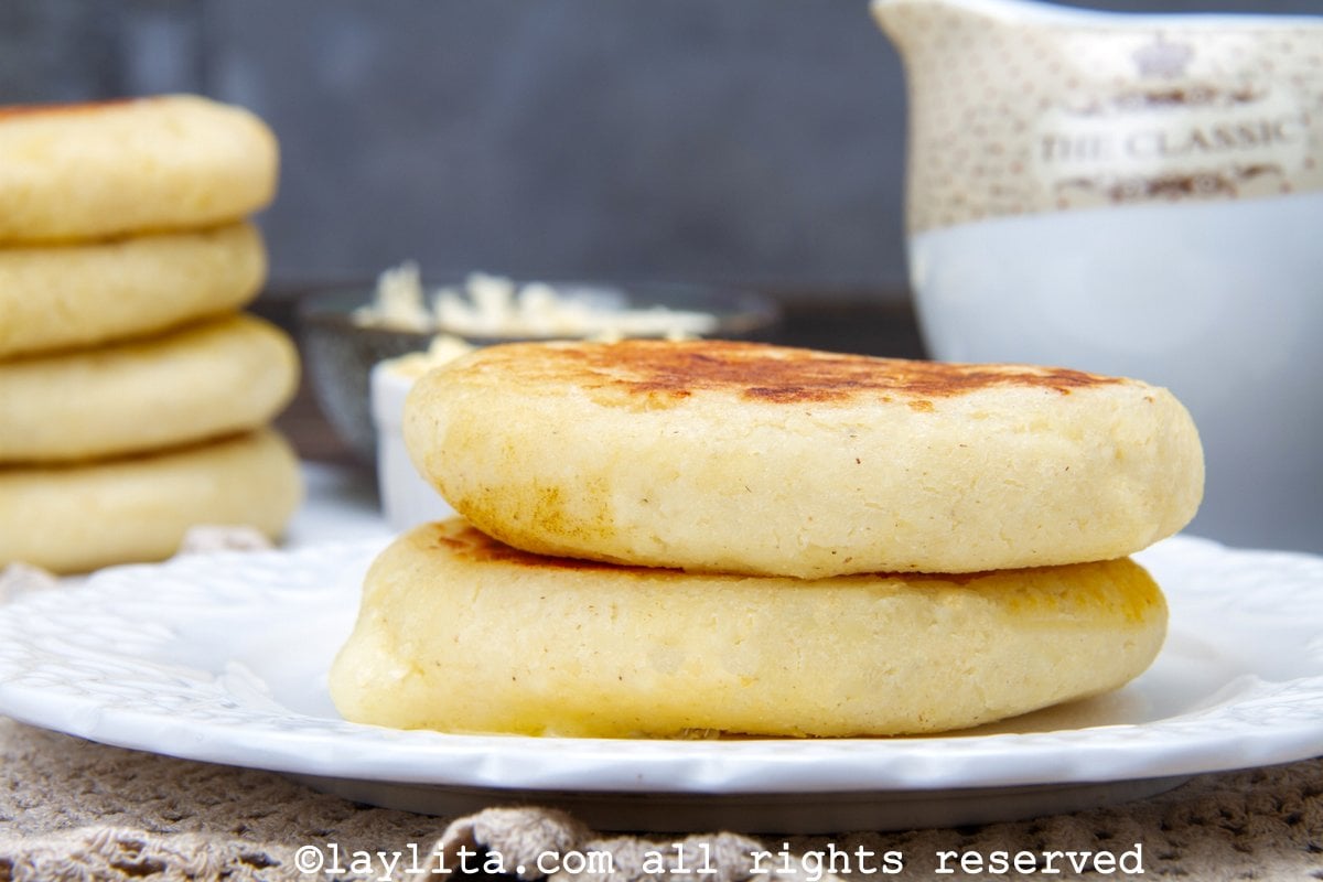 Side view of two cheese stuffed arepas stacked on a plate