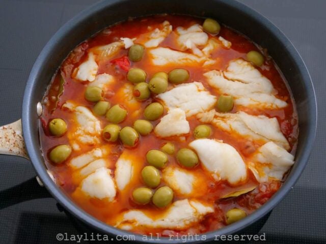 Adding the desalted cod fish and olives to the pan