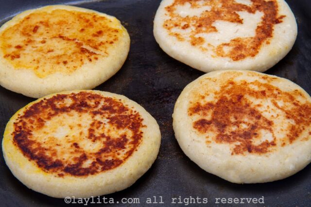 Cheese arepas cooking a griddle