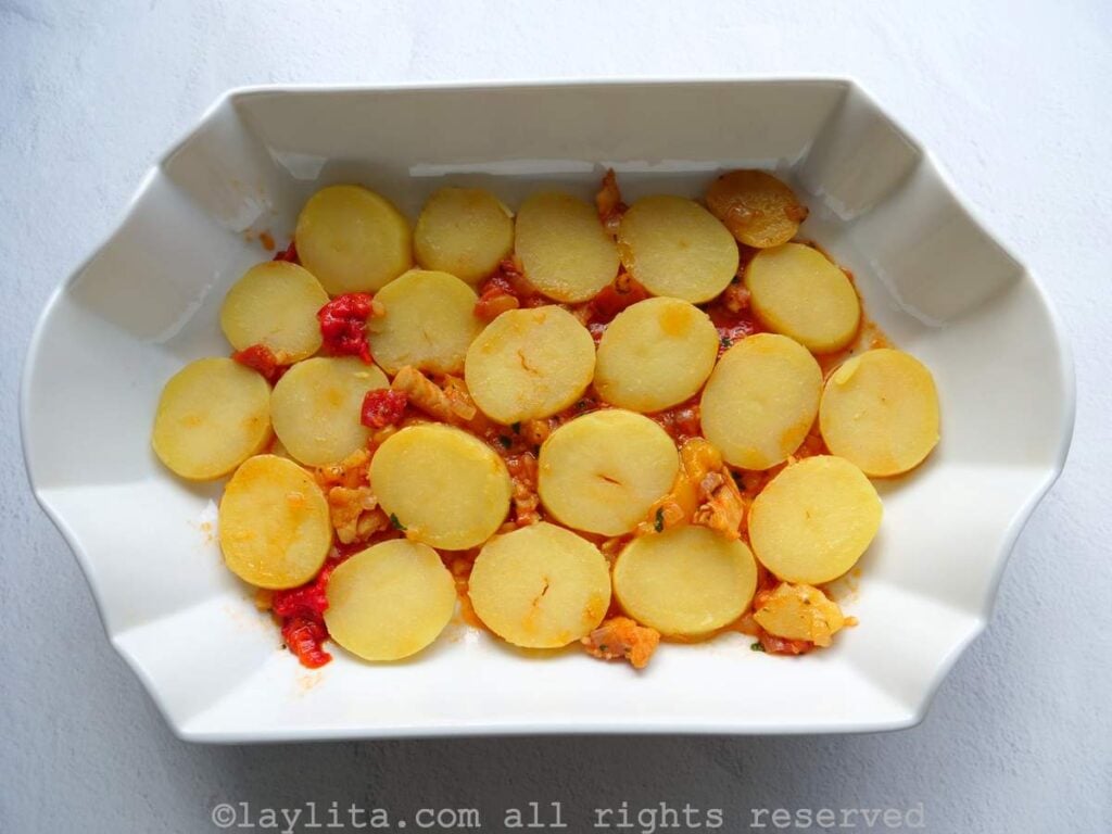 White baking pan with a layer of potatoes