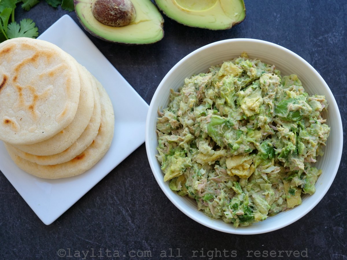 Overhead shot of avocado tuna salad filling in a bowl next to cooked arepas
