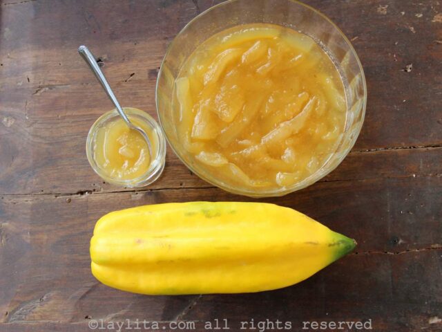 Overhead shot of a glass bowl of dulce de babaco next to a babaco fruit and small bowl of preserves.