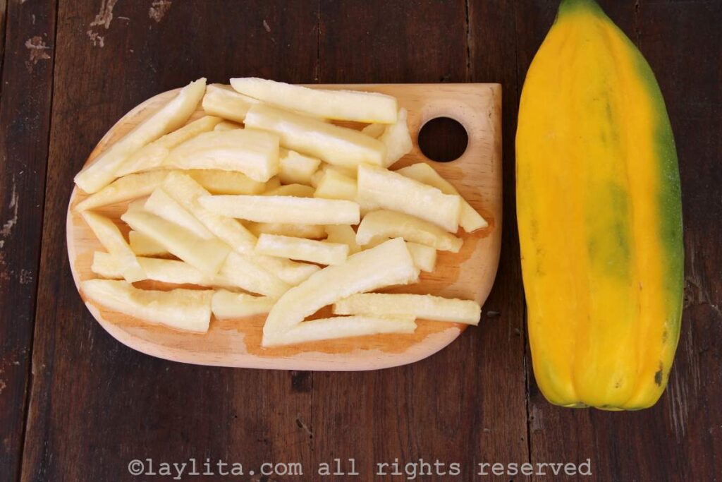 A ripe babaco fruit next to a cutting board with peeled and sliced babaco fruit pieces