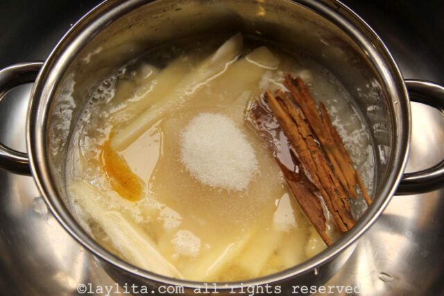 A pot filled with babaco pieces, sugar, cinnamon sticks, water and orange piel