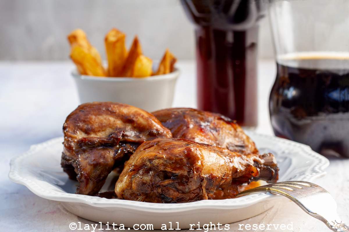 Side view of three pieces of coca cola chicken with a brown sticky glaze on top on a white plate.