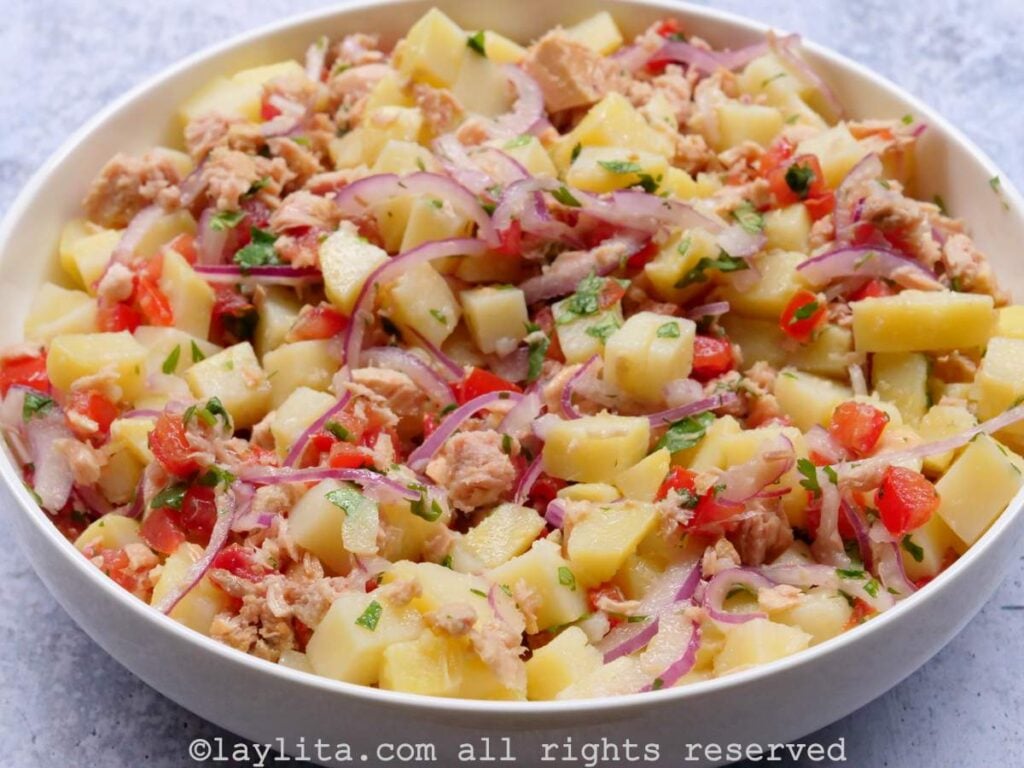 Overhead shot of Ecuadorian tuna potato salad mixed together and served in a shallow white dish.