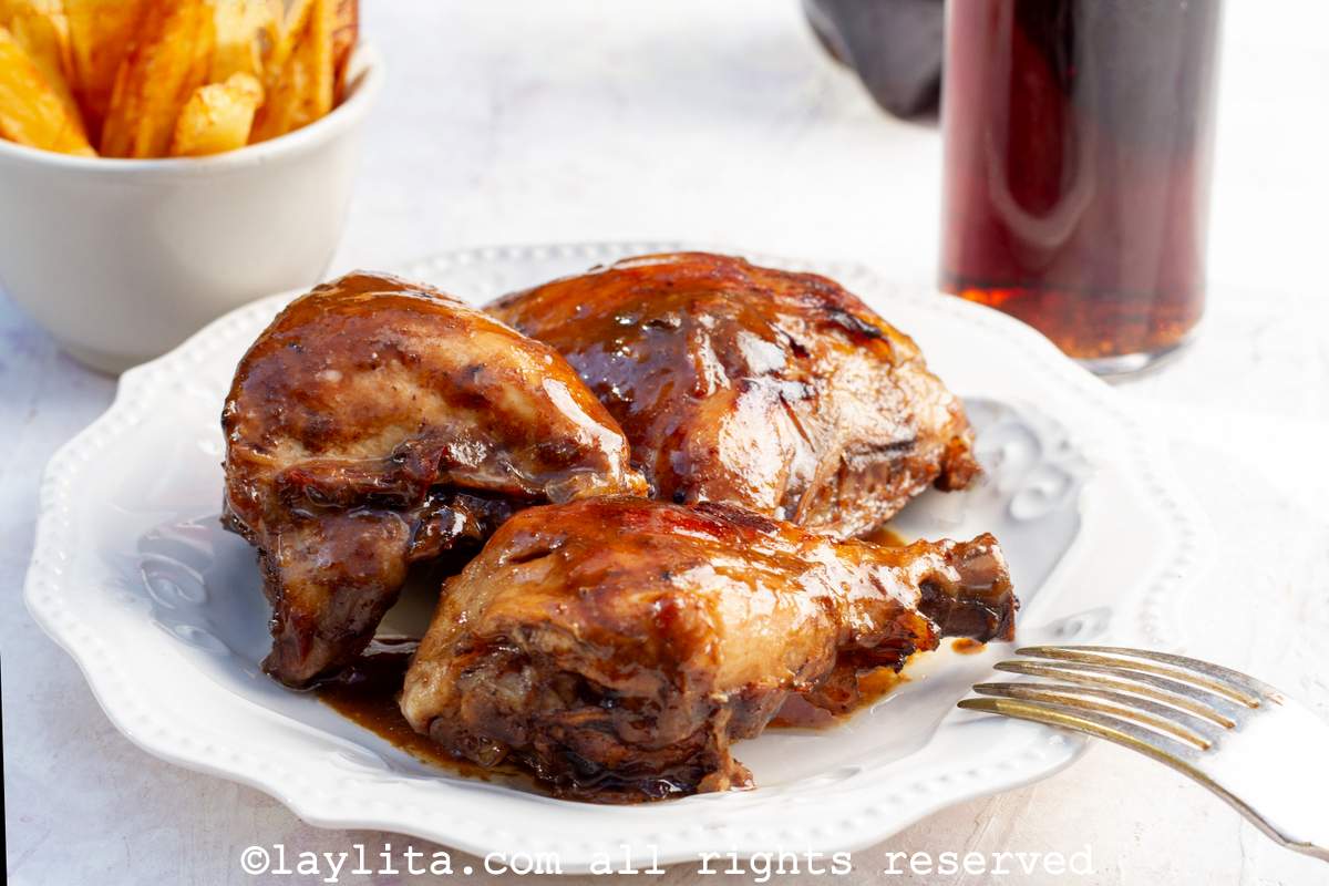 Close up of pollo a la coca cola served on a white plate with a sticky glaze on top.
