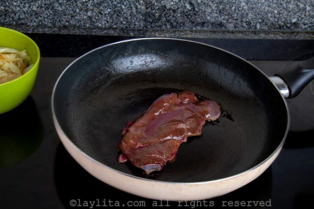 Preparing beef liver with onions in a skillet