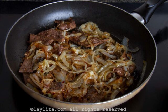 Preparing beef liver with onions or hígado encebollado in a skillet on the stove