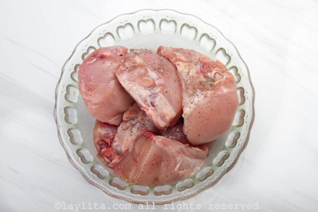 Chicken pieces marinating in a glass bowl