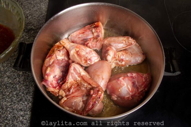 Chicken pieces being browned in a pan